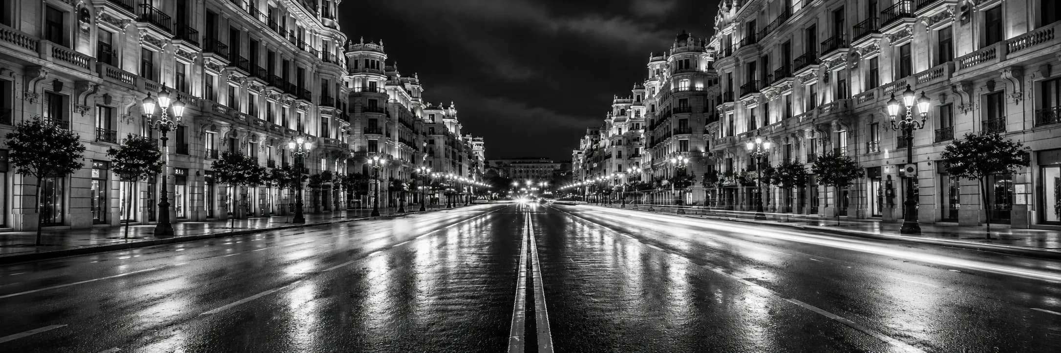 Madrid avenue at night, framed by illuminated architecture.
